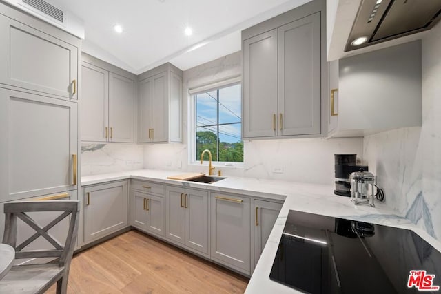 kitchen featuring light stone countertops, sink, gray cabinetry, and light wood-type flooring