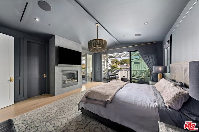 bedroom with a notable chandelier, lofted ceiling, access to exterior, and light hardwood / wood-style flooring