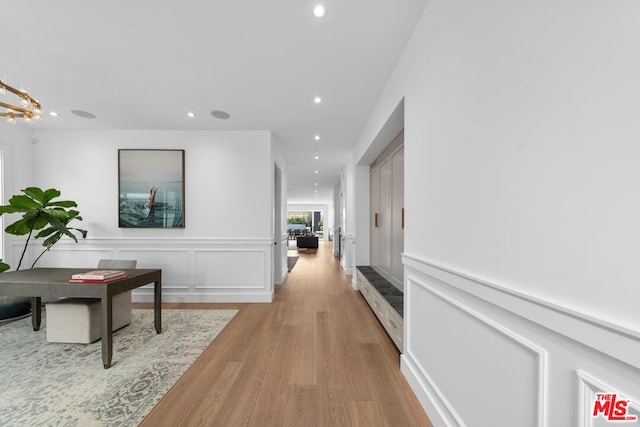 hall with a notable chandelier and light hardwood / wood-style flooring