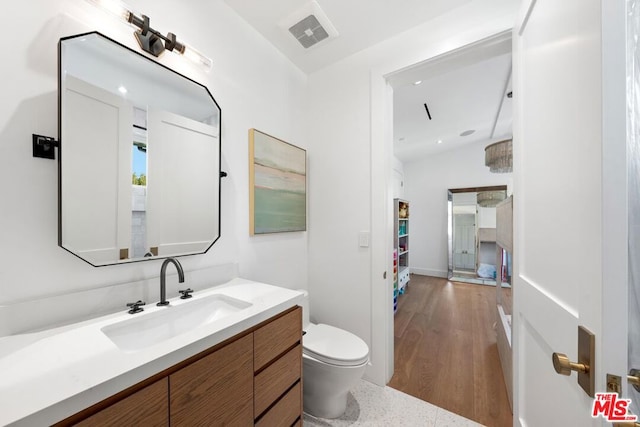 bathroom featuring hardwood / wood-style flooring, vanity, lofted ceiling, and toilet