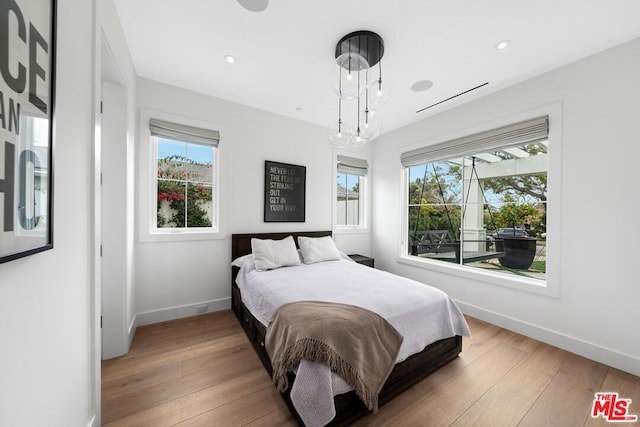 bedroom featuring wood-type flooring and a notable chandelier