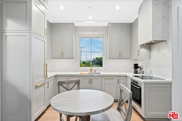 kitchen with gray cabinets, sink, stainless steel oven, custom range hood, and black electric cooktop