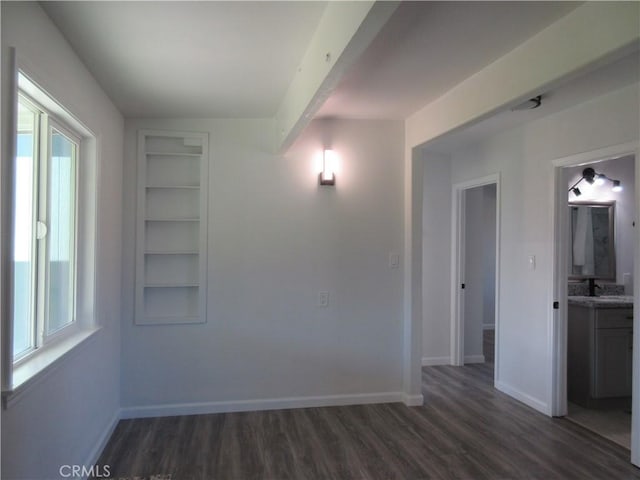 spare room featuring plenty of natural light, built in features, and dark hardwood / wood-style floors