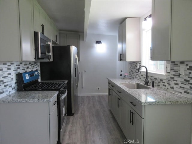 kitchen featuring sink, dark wood-type flooring, appliances with stainless steel finishes, white cabinetry, and light stone counters