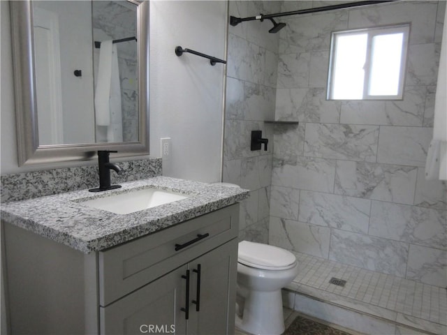 bathroom featuring vanity, toilet, and a tile shower