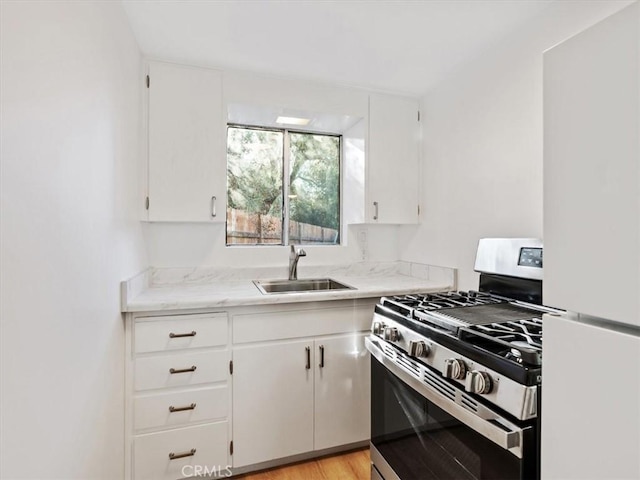 kitchen with white cabinetry, white refrigerator, sink, and stainless steel gas stove