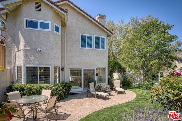 back of property with a yard and a patio area