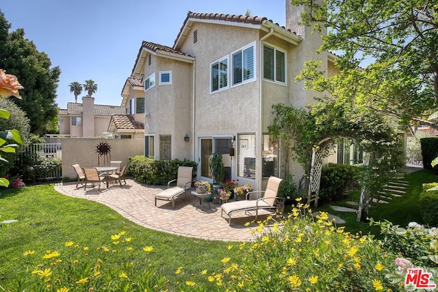 back of property with a lawn and a patio area