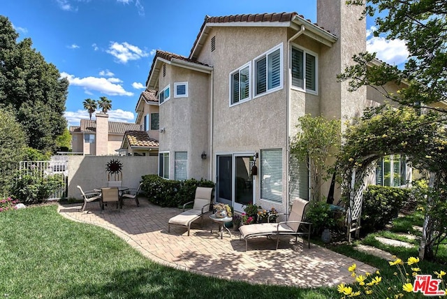 back of house featuring a patio area and a lawn