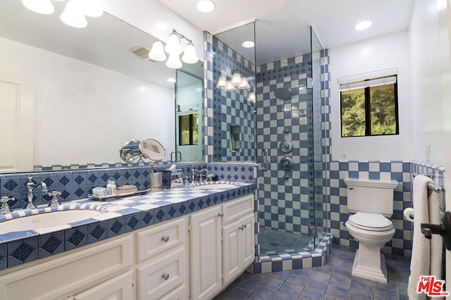 bathroom featuring walk in shower, toilet, tile walls, vanity, and tile patterned flooring