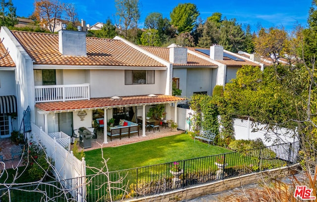 rear view of house with an outdoor hangout area, a patio, a balcony, and a lawn