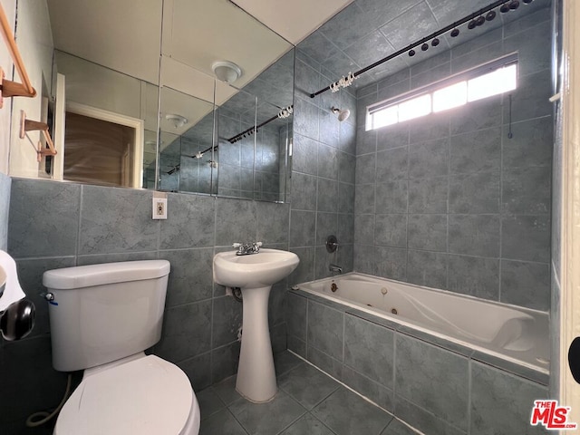 bathroom featuring tiled shower / bath combo, tile walls, tile patterned floors, and toilet