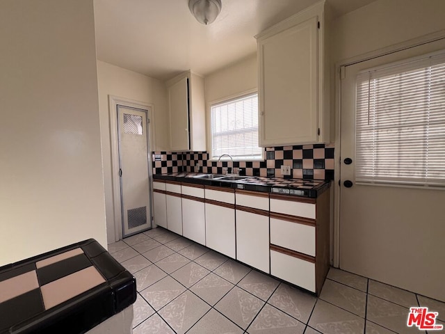 kitchen featuring sink, white cabinetry, backsplash, light tile patterned flooring, and tile countertops