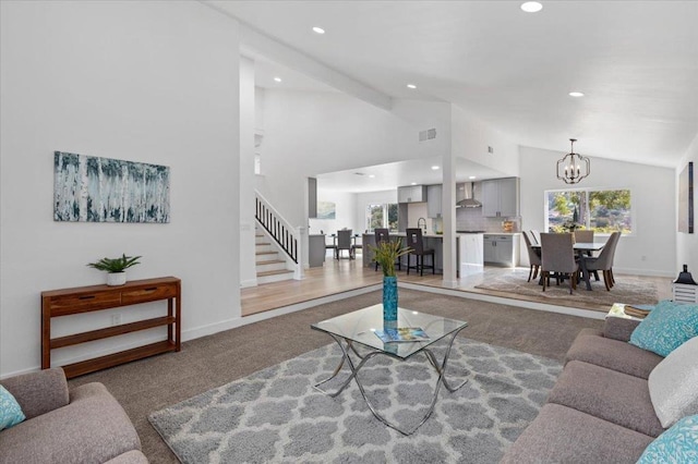 carpeted living room featuring an inviting chandelier, lofted ceiling with beams, and a wealth of natural light