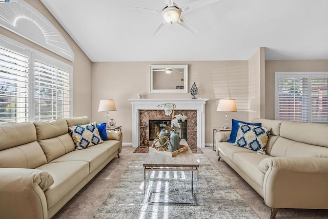 carpeted living room with a high end fireplace and ceiling fan