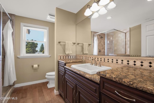 bathroom with an inviting chandelier, vanity, a shower with door, hardwood / wood-style flooring, and backsplash