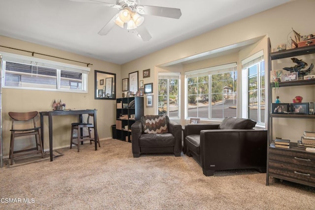 living area with light carpet and ceiling fan