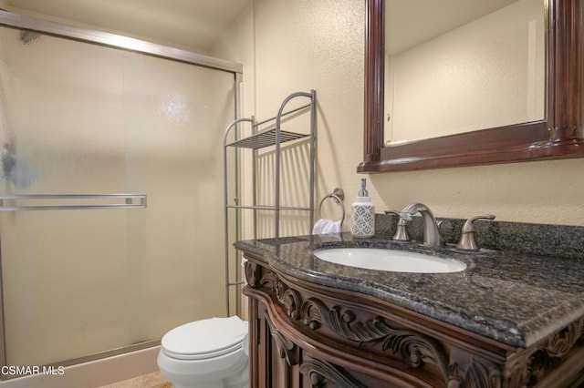 bathroom featuring vanity, toilet, and a shower with shower door