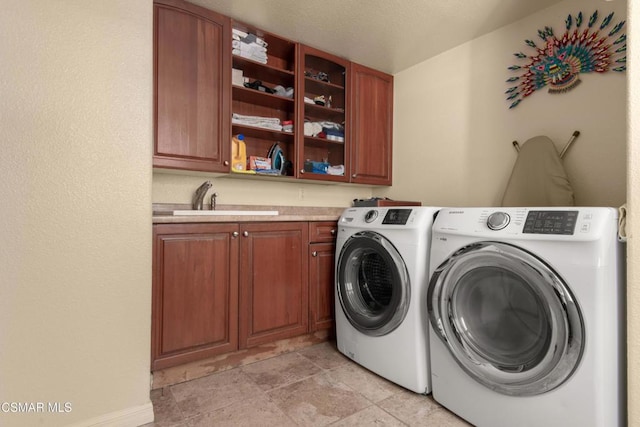 laundry area featuring washer and dryer, sink, and cabinets