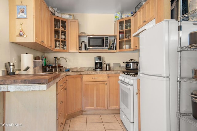 kitchen with light brown cabinetry, sink, white appliances, and light tile patterned floors