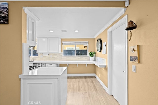 kitchen with light hardwood / wood-style flooring, white cabinetry, backsplash, ornamental molding, and kitchen peninsula