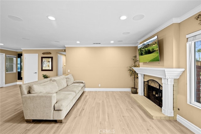 living room featuring crown molding, a fireplace, and light wood-type flooring