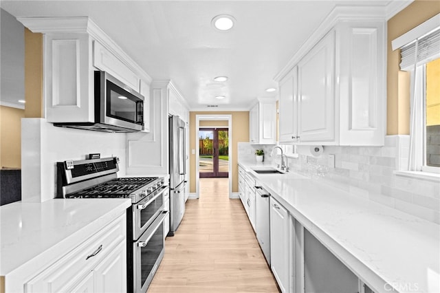 kitchen featuring white cabinetry, appliances with stainless steel finishes, sink, and light stone counters