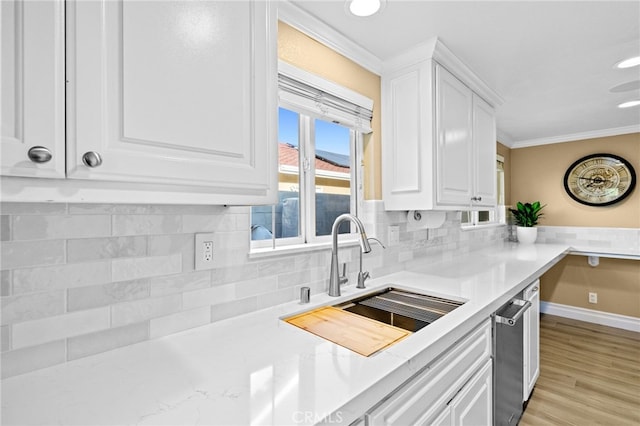 kitchen with sink, crown molding, light hardwood / wood-style flooring, white cabinetry, and backsplash