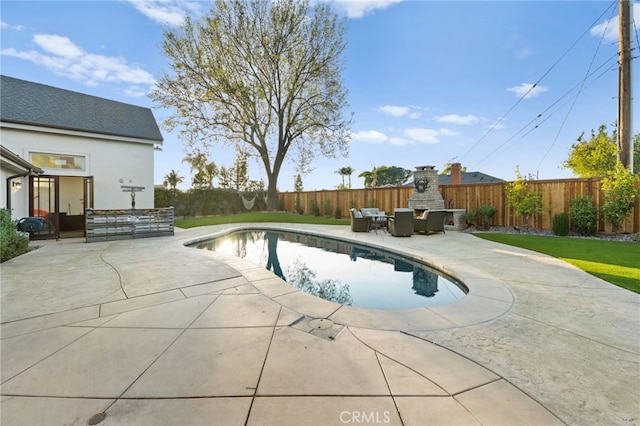 view of pool with exterior fireplace and a patio area