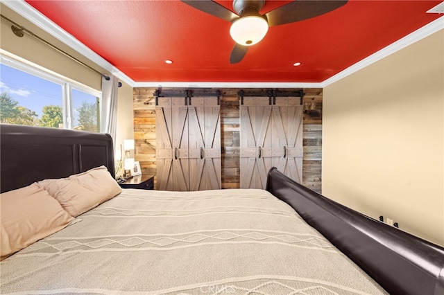 bedroom featuring crown molding, wooden walls, and a barn door