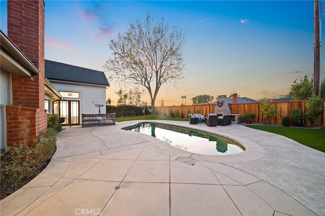 pool at dusk featuring a patio area and an outdoor fireplace