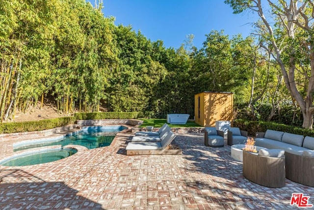 view of patio / terrace with an in ground hot tub, an outdoor living space with a fire pit, and a storage unit