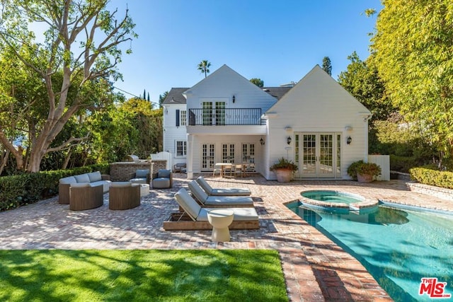 back of house featuring french doors, a patio area, a balcony, outdoor lounge area, and an in ground hot tub