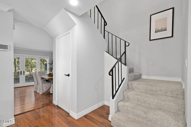 stairs with wood-type flooring, vaulted ceiling, and french doors