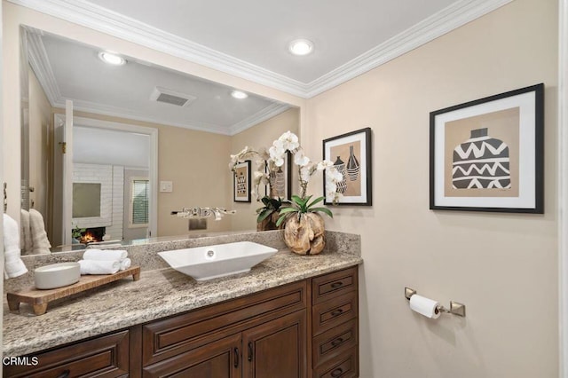 bathroom featuring crown molding, a large fireplace, and vanity