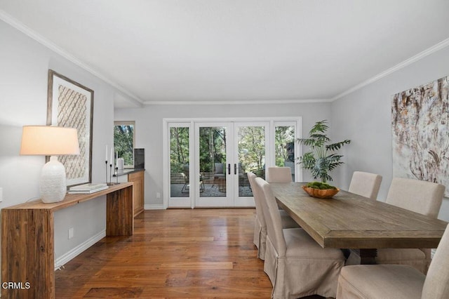 dining area featuring wood-type flooring, ornamental molding, and french doors