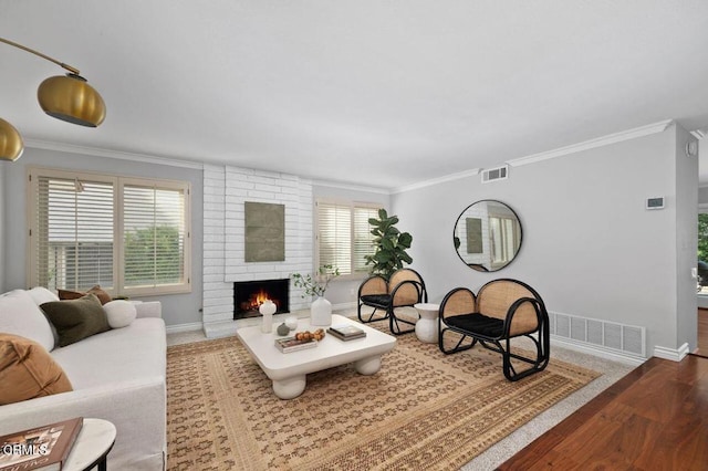 living room with hardwood / wood-style floors, ornamental molding, and a large fireplace