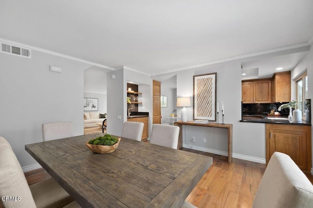 dining room featuring crown molding and light hardwood / wood-style flooring