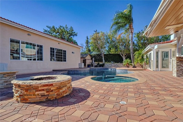 view of swimming pool featuring an in ground hot tub, an outdoor fire pit, and a patio