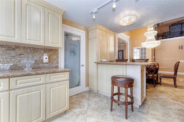 kitchen featuring decorative light fixtures, a kitchen breakfast bar, decorative backsplash, and cream cabinetry