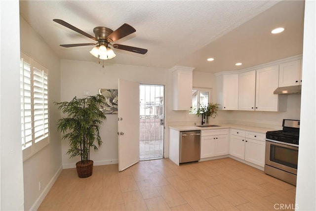 kitchen featuring appliances with stainless steel finishes, sink, white cabinets, and ceiling fan