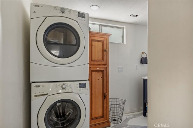 laundry room with stacked washer and dryer and cabinets