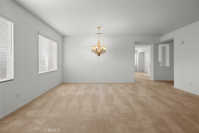 carpeted spare room featuring a chandelier