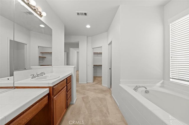 bathroom with vanity and tiled tub