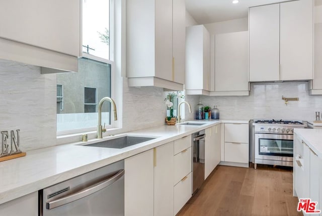 kitchen with backsplash, stainless steel appliances, sink, and white cabinets