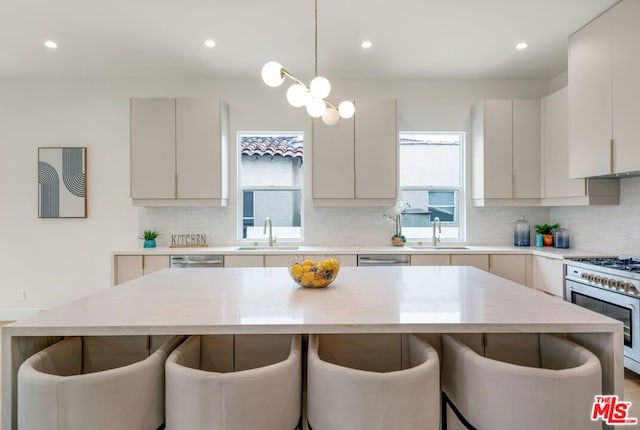 kitchen with stainless steel appliances, a breakfast bar, sink, and hanging light fixtures