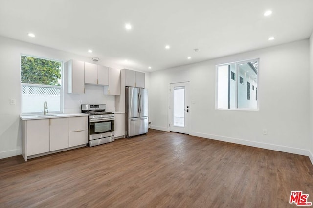 kitchen with sink, hardwood / wood-style floors, white cabinets, and appliances with stainless steel finishes