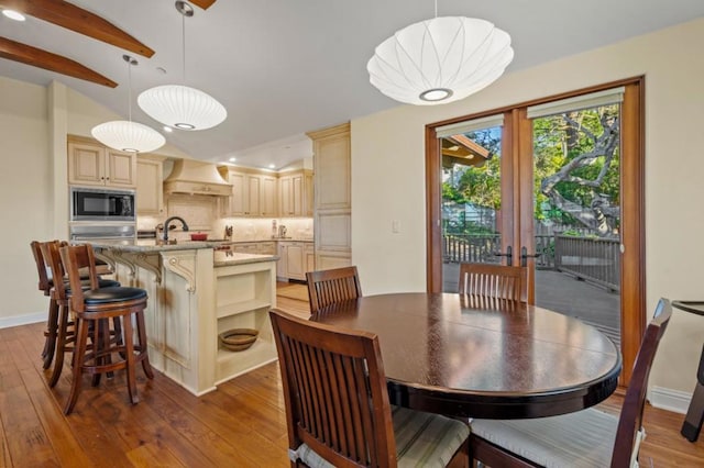 dining space featuring hardwood / wood-style flooring, lofted ceiling with beams, sink, and french doors