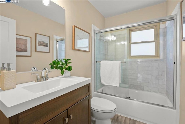 full bathroom with vanity, combined bath / shower with glass door, wood-type flooring, and toilet