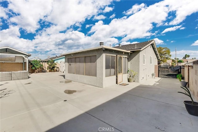 back of house featuring a gate, a patio area, a fenced backyard, and stucco siding